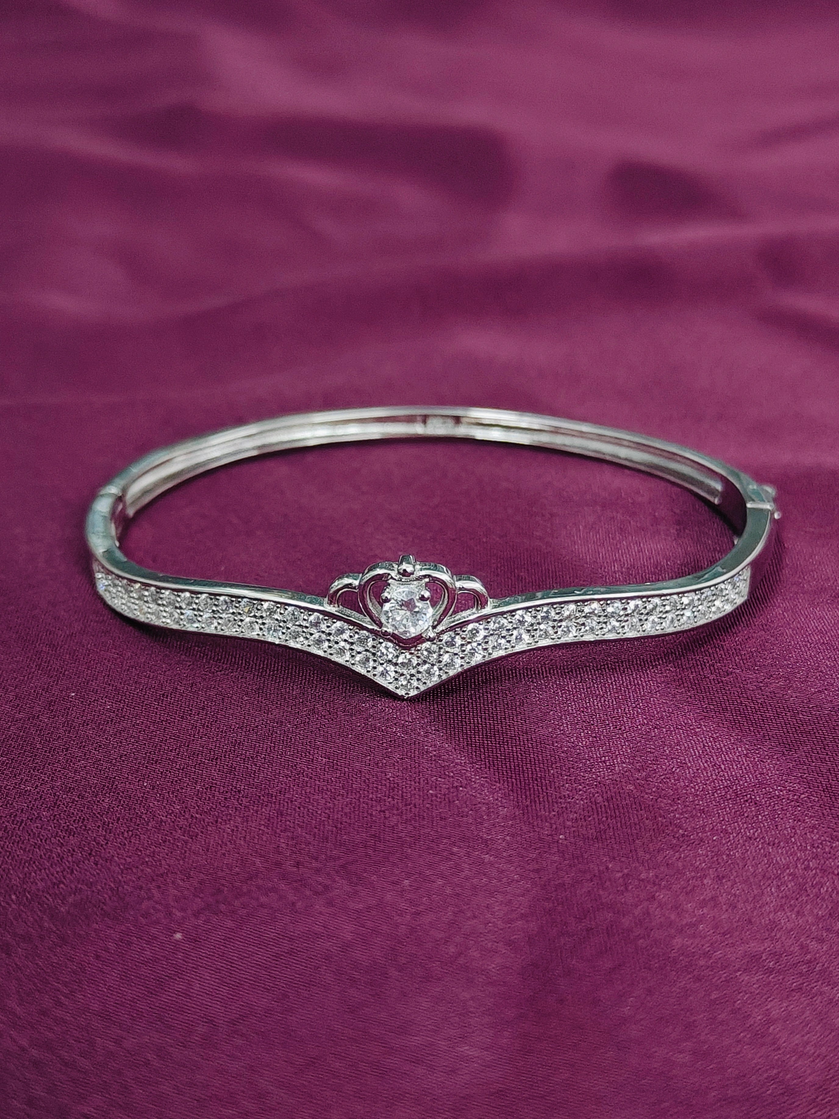 Silver bracelet with a heart design on a purple fabric background